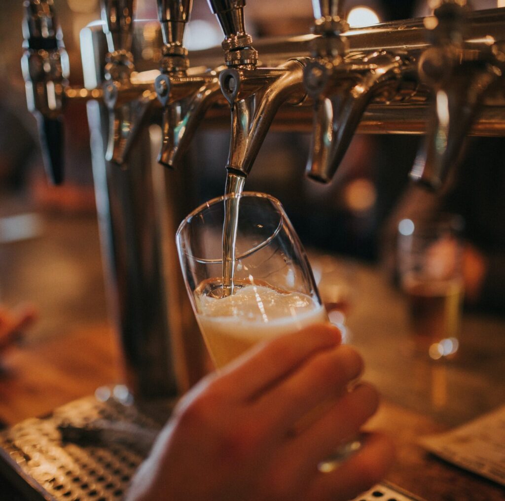 A glass of craft beer being poured from a bar tap