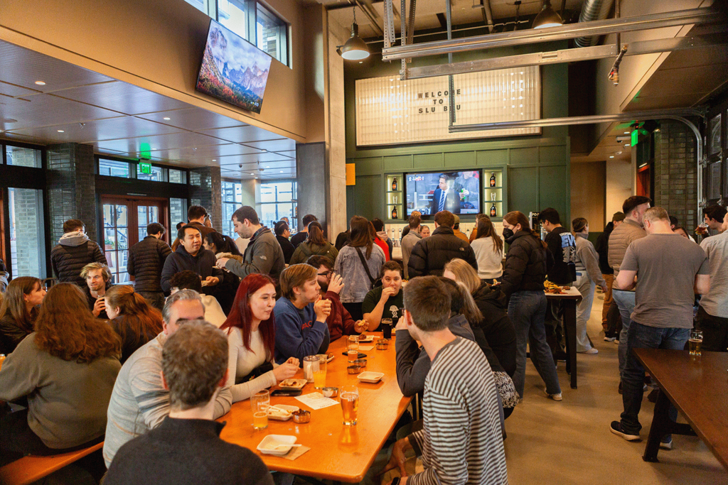 Inside SLU BRU in Seattle, a lively crowd gathers at tables, creating a vibrant dining atmosphere.