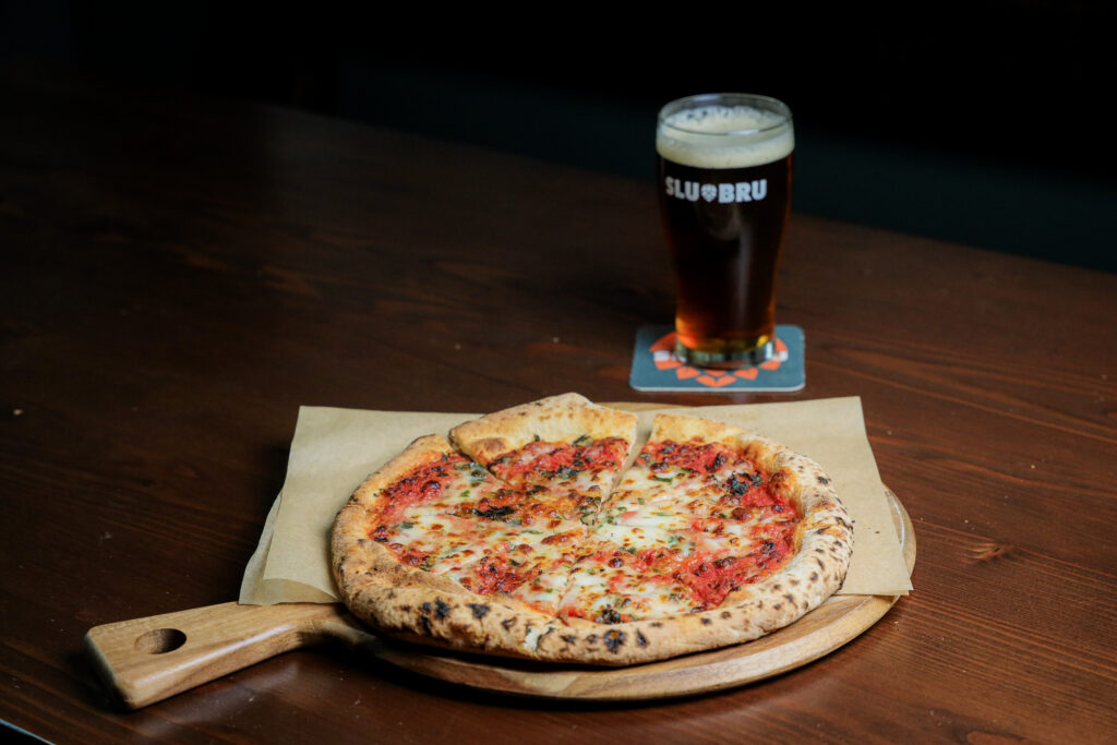 A classic Margherita pizza with fresh mozzarella, tomato, and basil, paired with a cold beer on a table in Seattle.